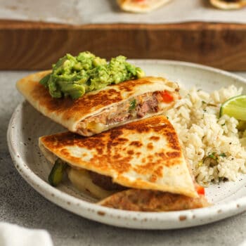 Side shot of two quesadillas stacked on a plate with rice.
