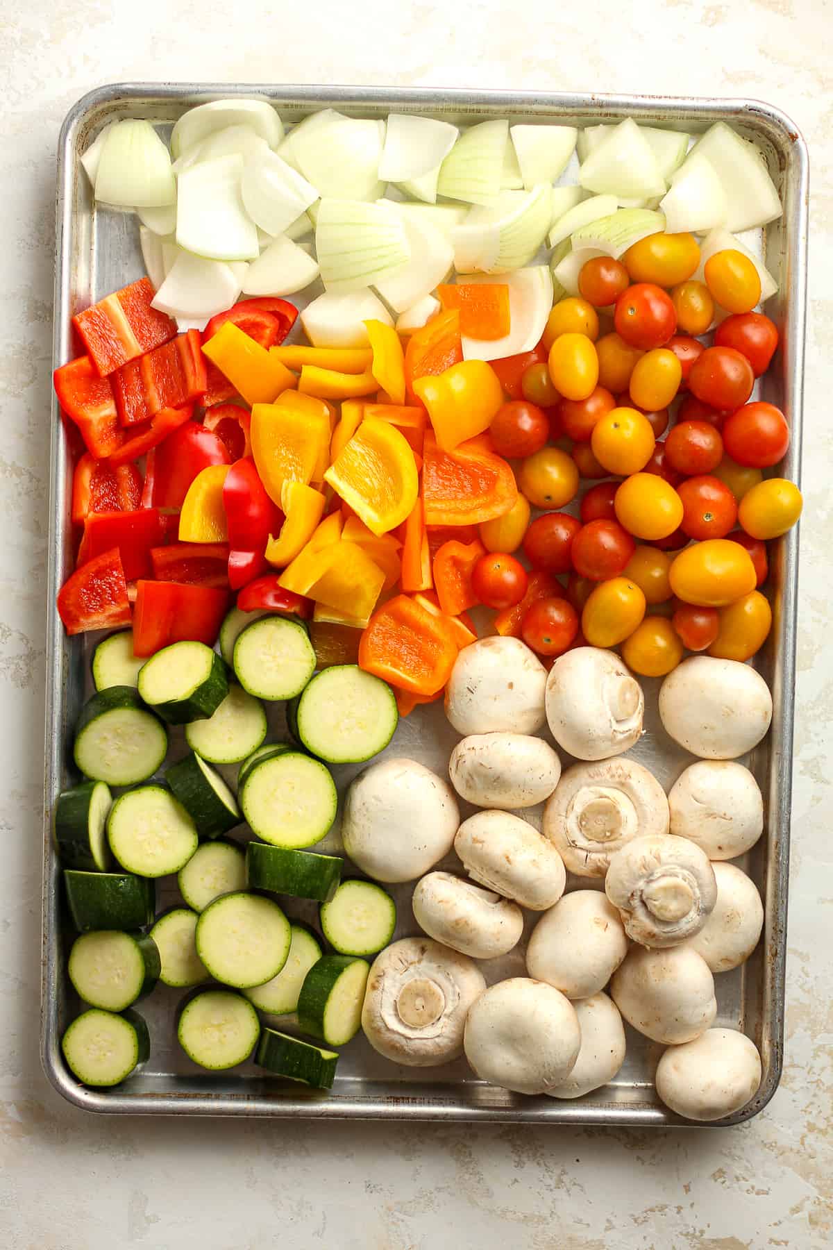 A sheet pan of veggies - onions, peppers, cherry tomatoes, zucchini, mushrooms.