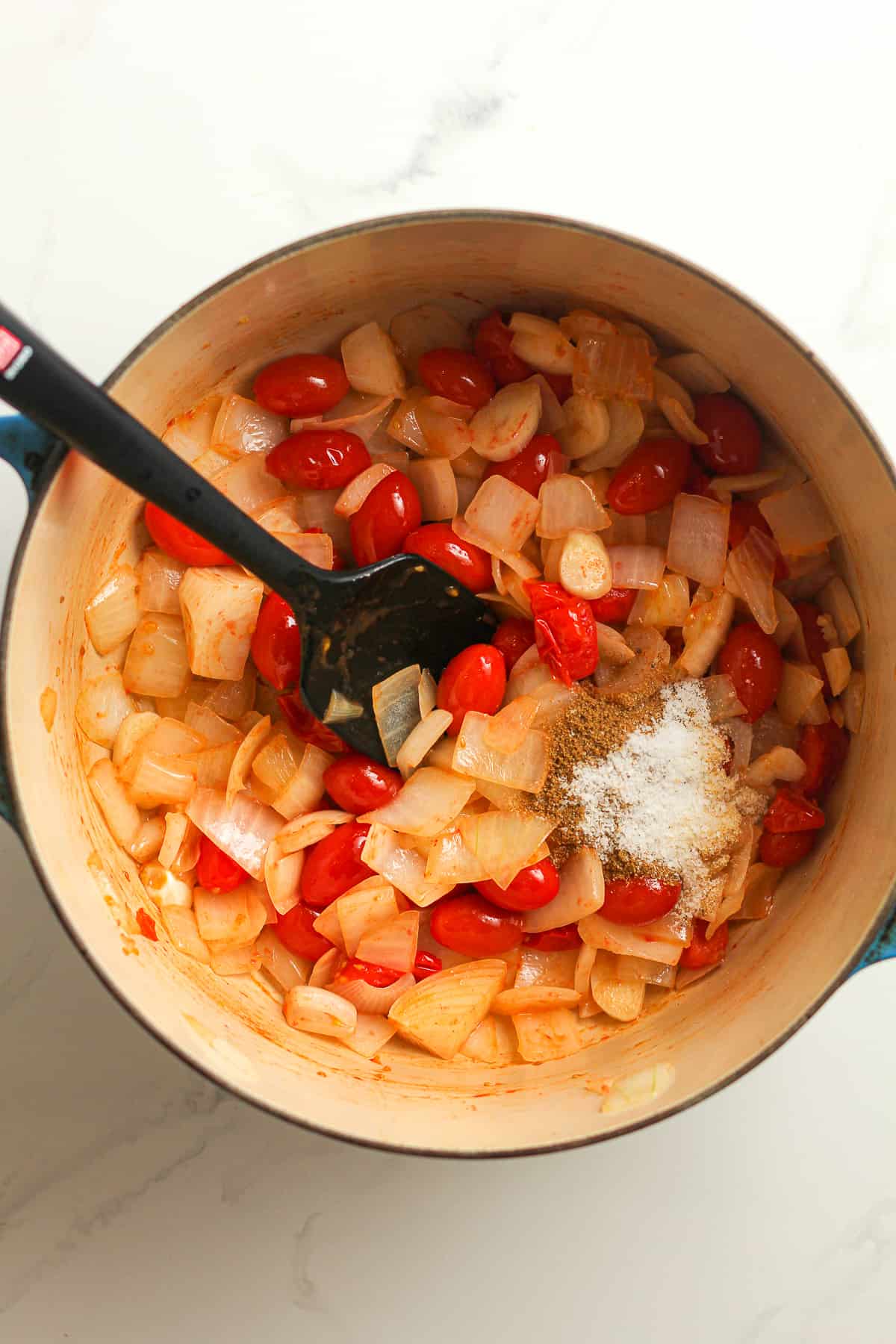 A pot of the cooked onions, tomatoes, garlic and the seasoning on top.