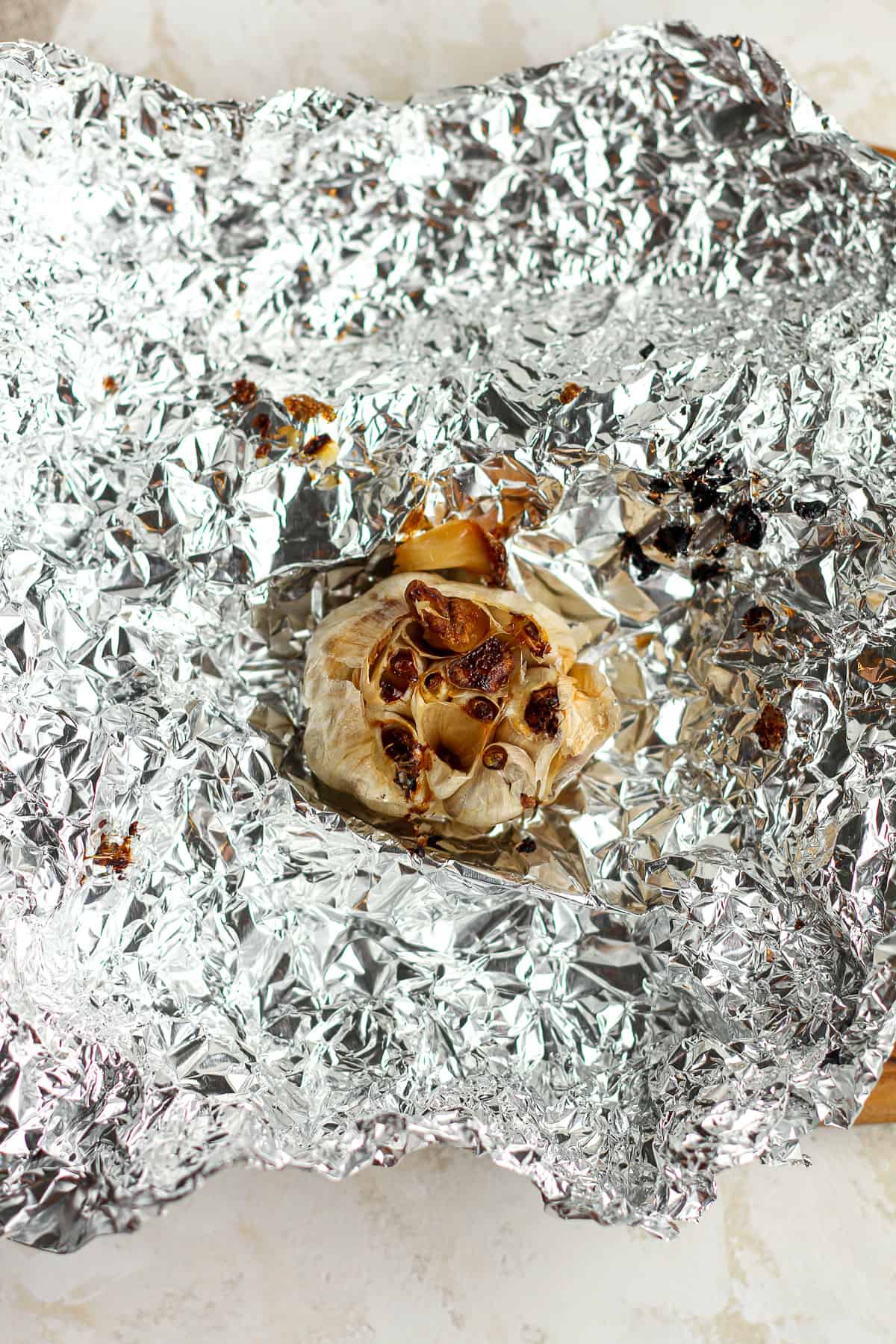 A bulb of roasted garlic on some tin foil.