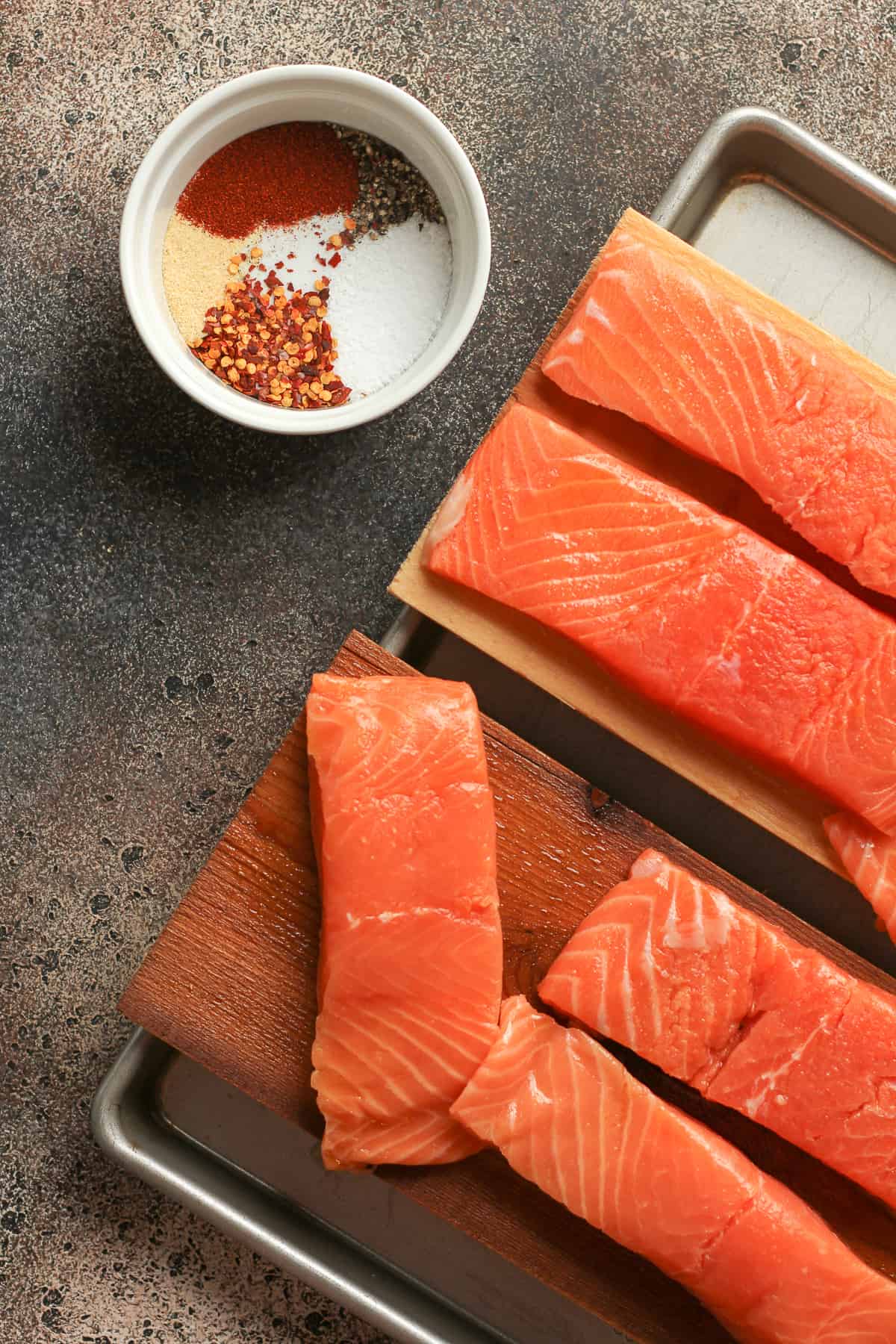 A partial shot of the salmon on planks with a bowl of seasoning.