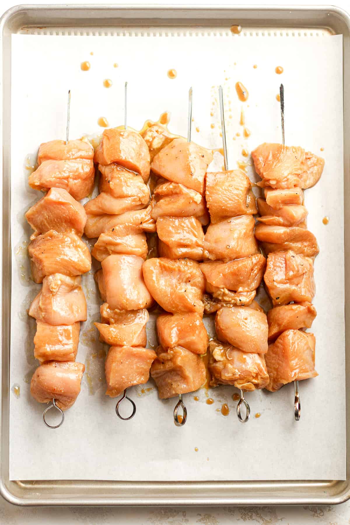 A pan of raw skewered and marinated chicken.