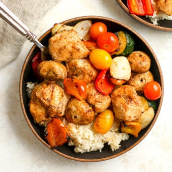 Closeup on a bowl of chunks of juicy chicken and veggies, over rice.