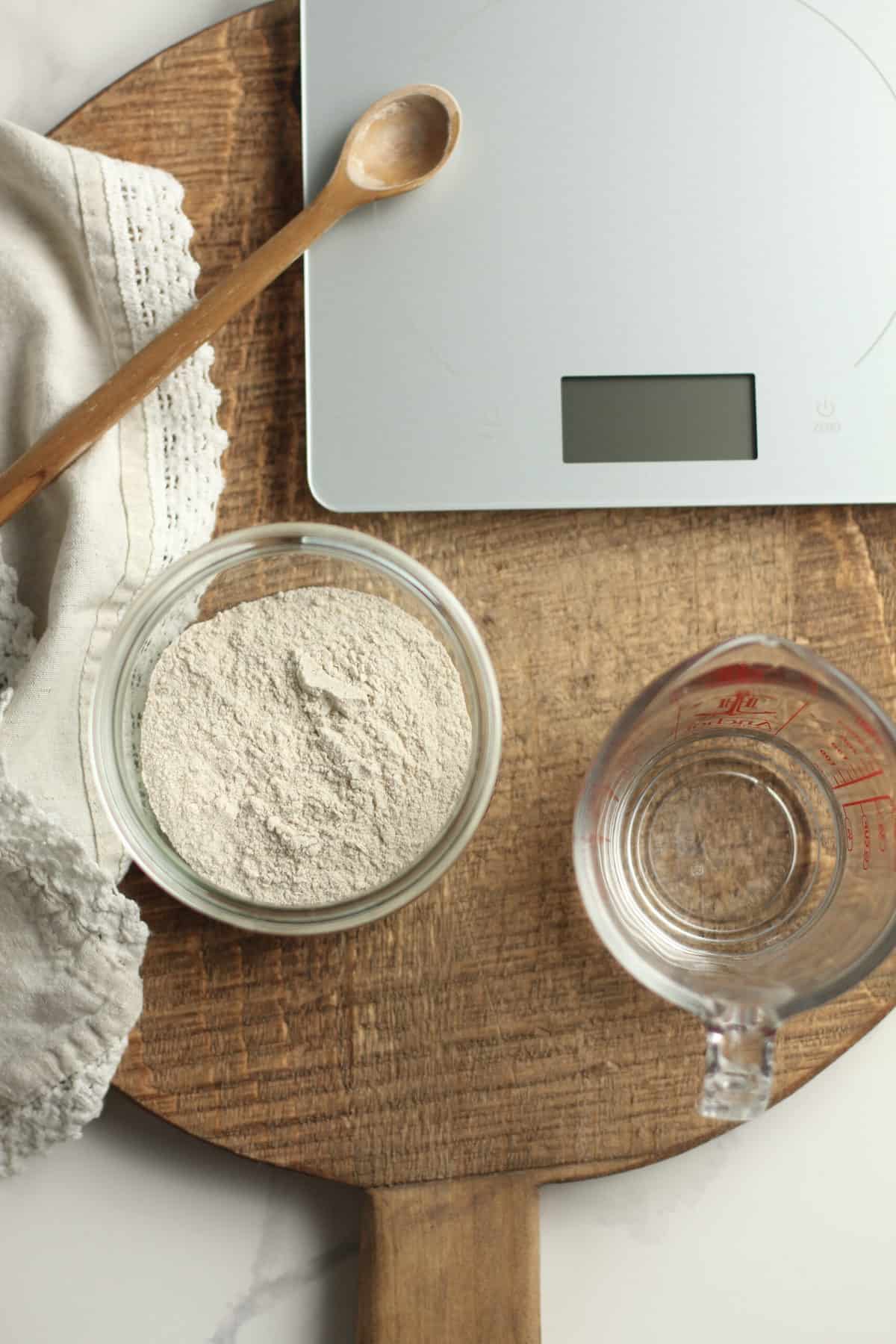 Tools used for initial feeding, including a scale, flour, and a measuring cup of water.