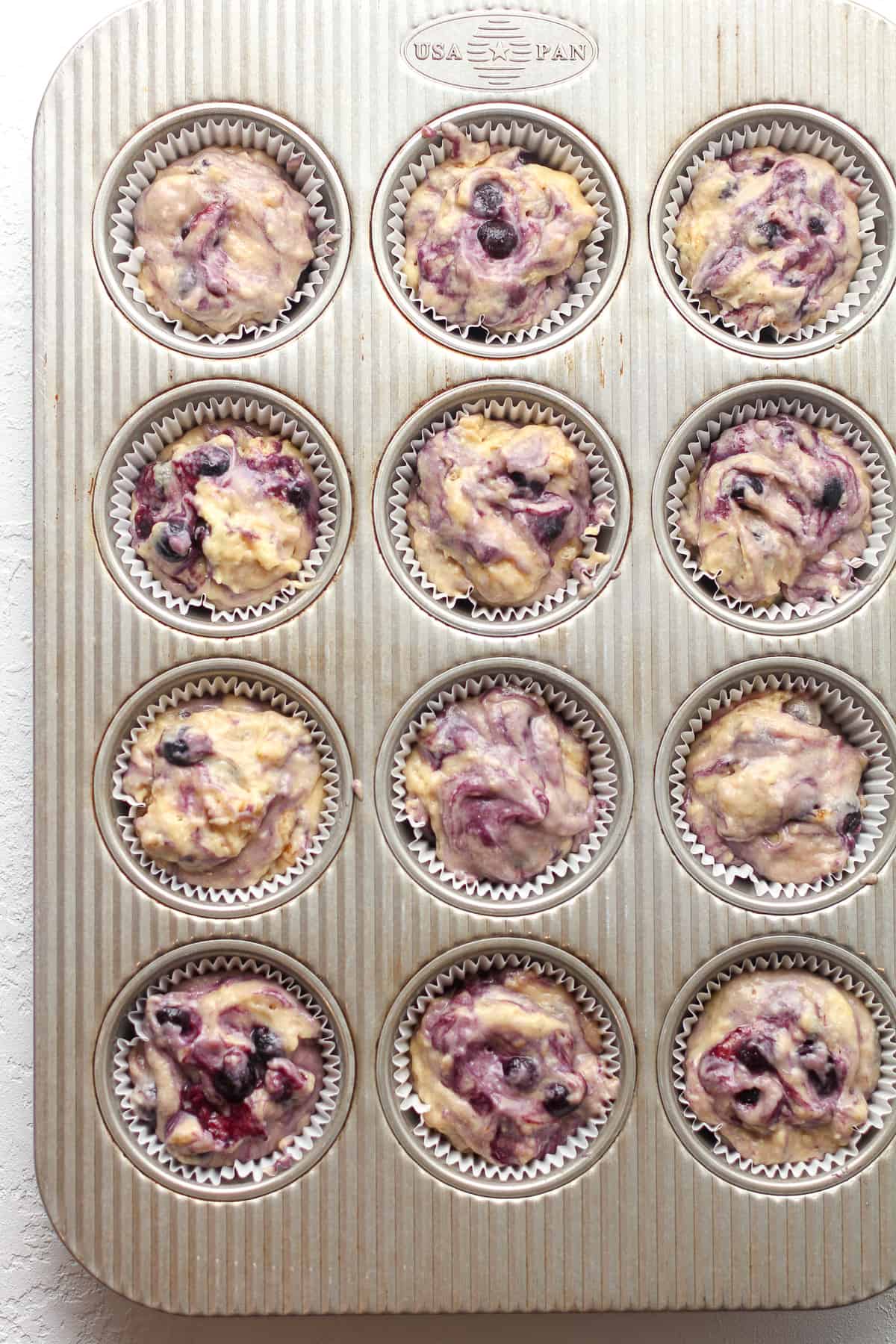 The muffin batter in a muffin tin.
