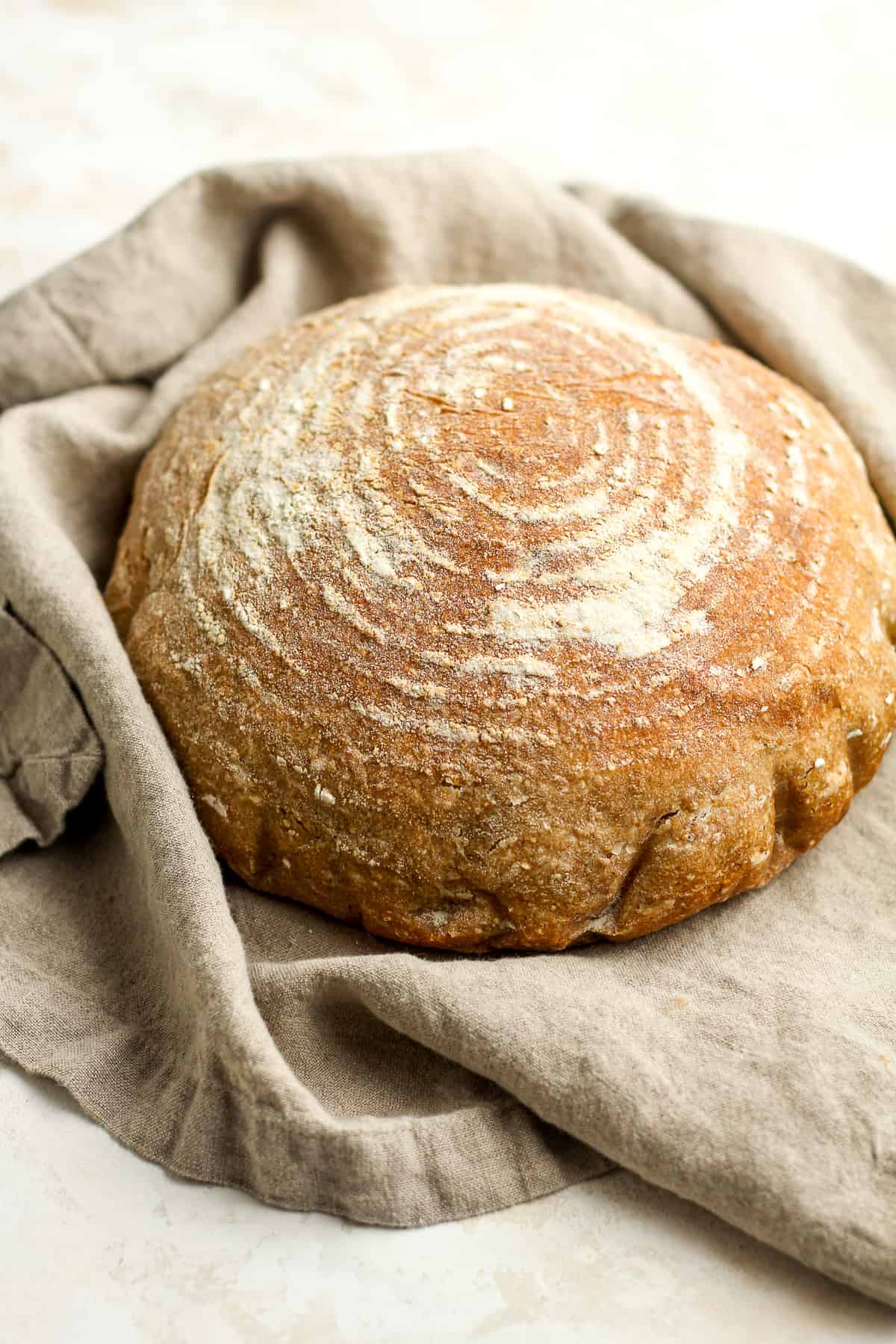 Side view of a round loaf of just baked multigrain sourdough.