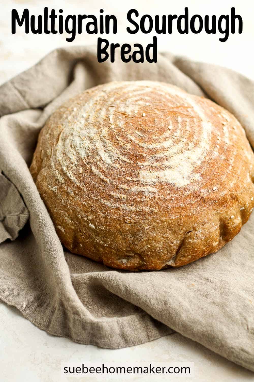 Side view of a round loaf of multigrain sourdough on a gray napkin.