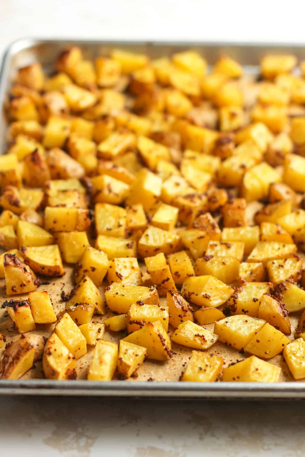 Side view of a sheet pan of mustard roasted potatoes.