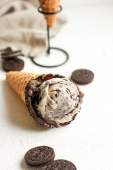Side view of a cone laying on it's side, filled with Oreo ice cream.