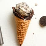 A waffle cone with some Oreo ice cream inside.