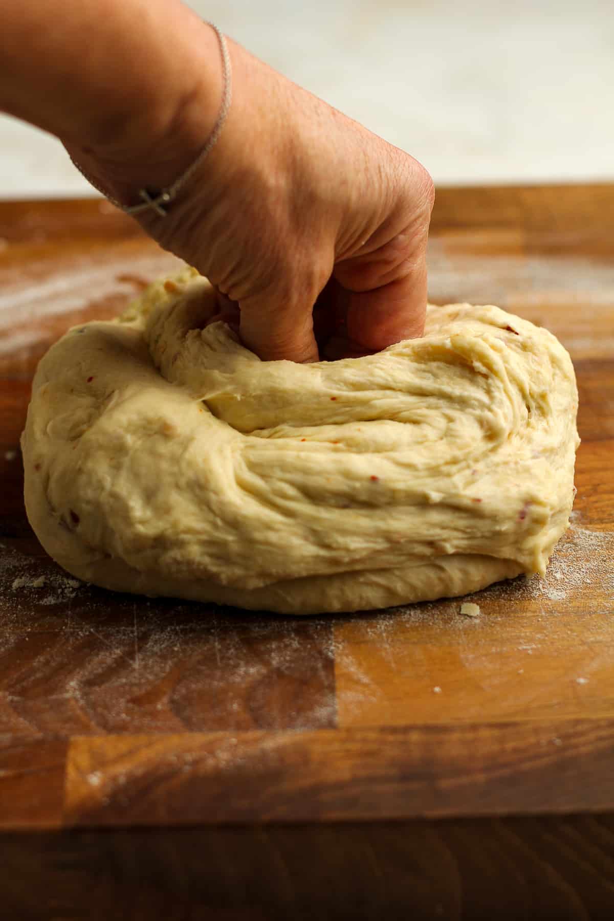 My hand pushing into a round of flatbread dough.