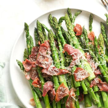 A plate with roasted asparagus with parmesan and prosciutto.