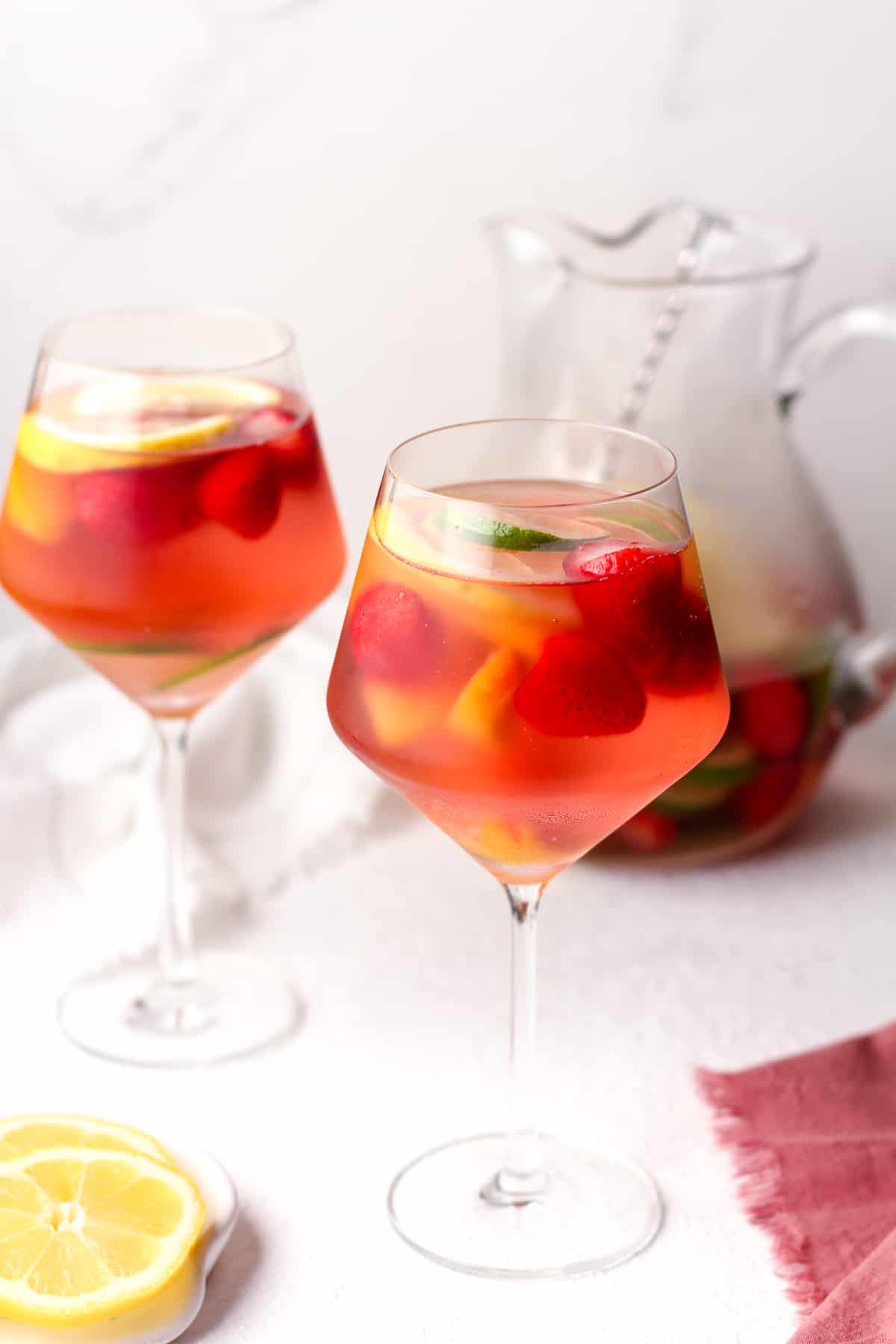 Side view of two glasses of sangria on a white background.