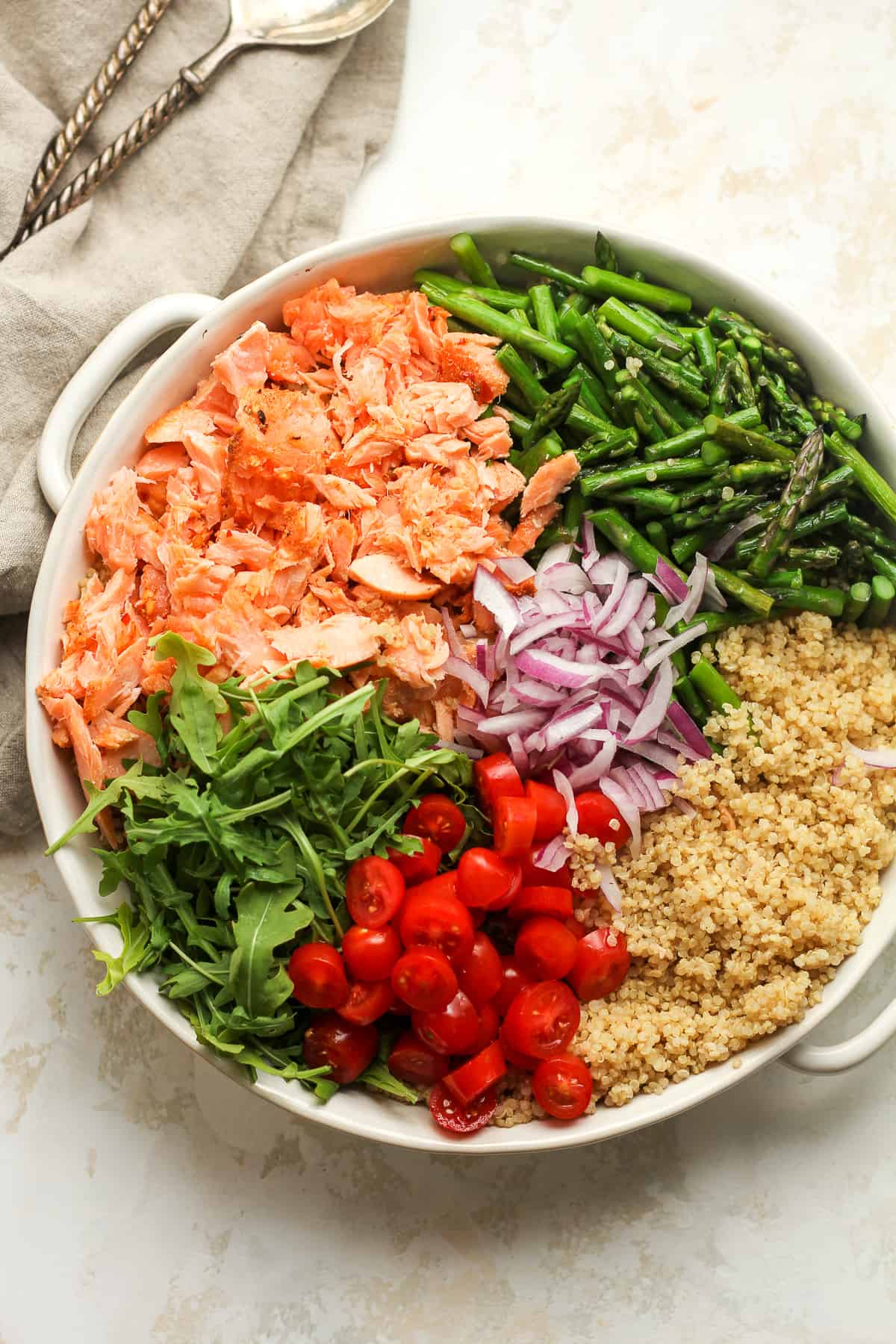 A round bowl of the salmon quinoa salad, separated by ingredient.