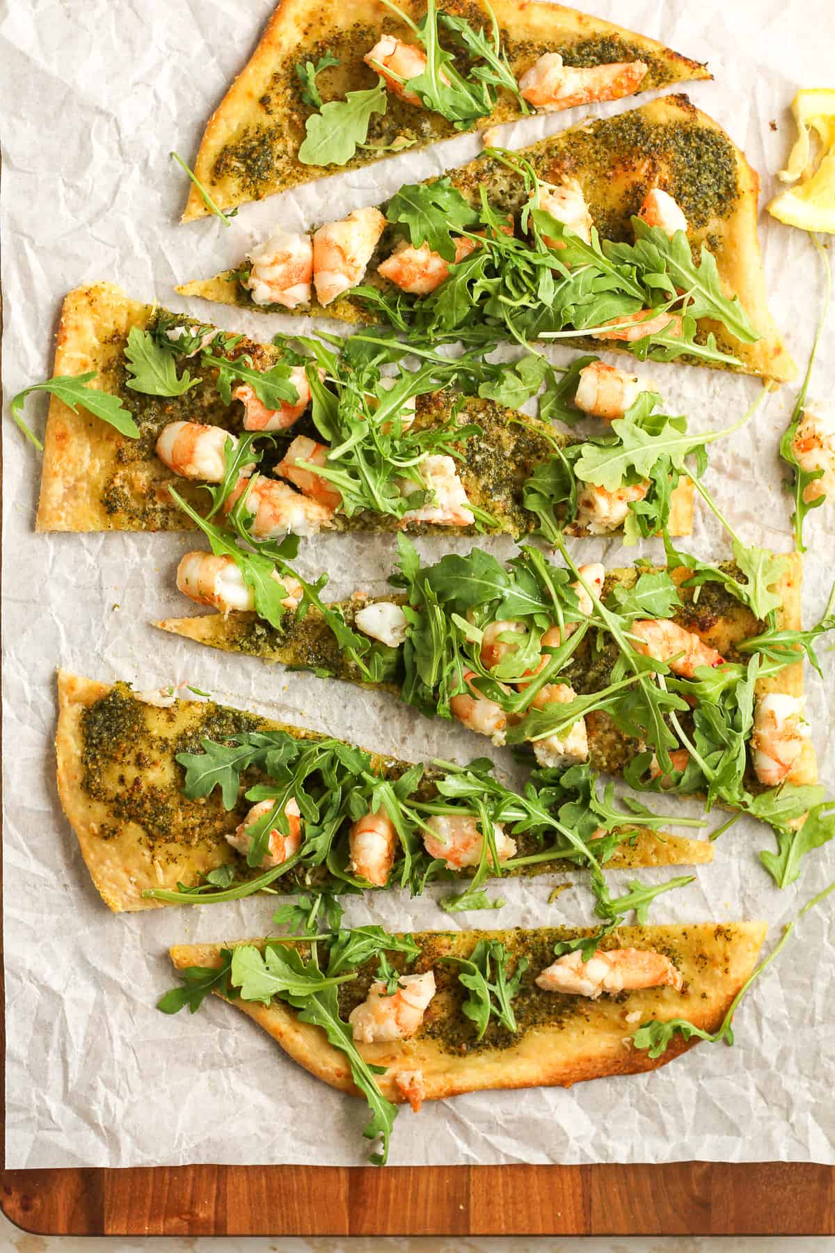 Sliced flatbread pizza with pesto and shrimp.