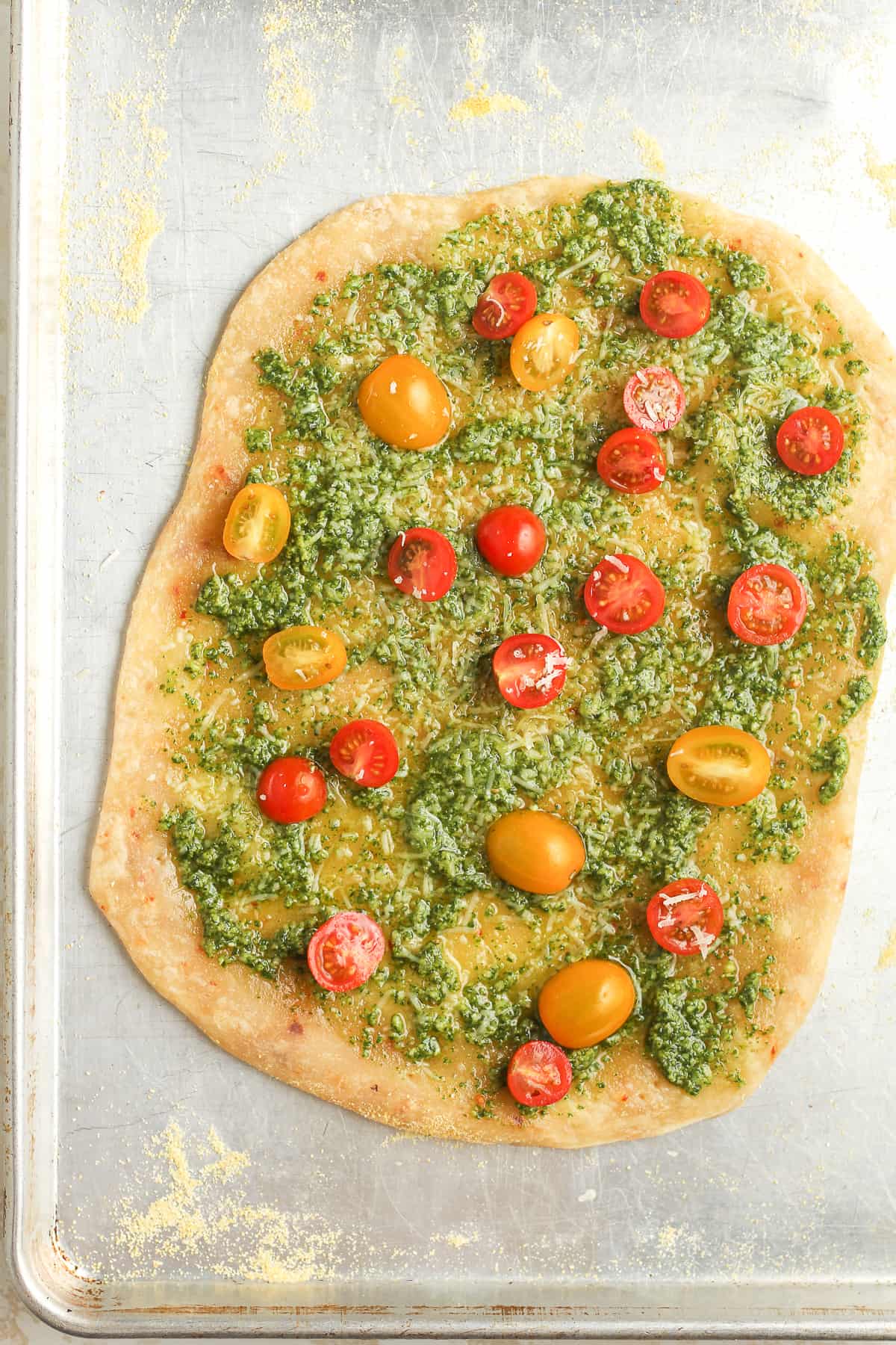 The flatbread crust after pre-baking with pesto and tomatoes.
