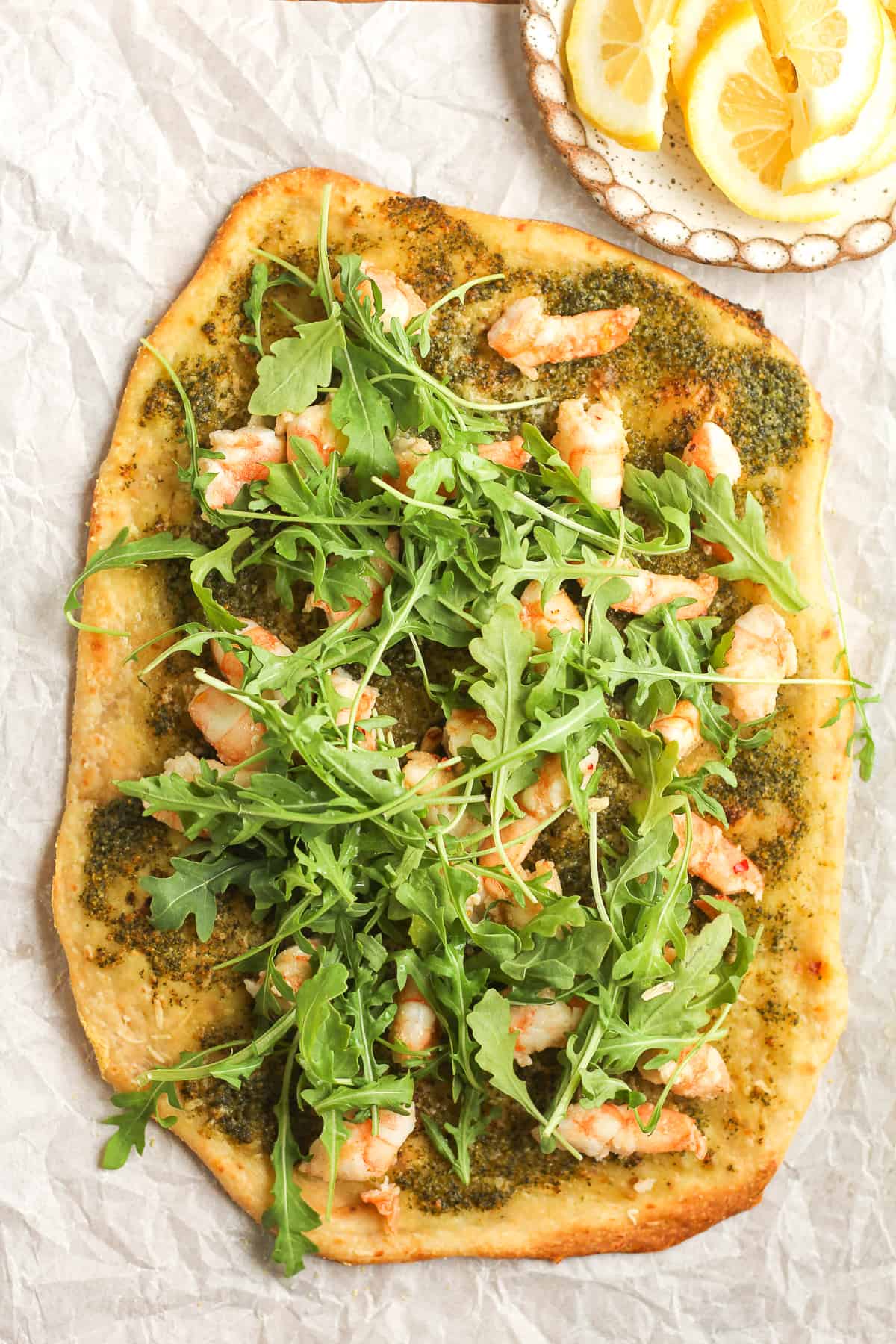 A flatbread pizza just baked with shrimp and arugula.