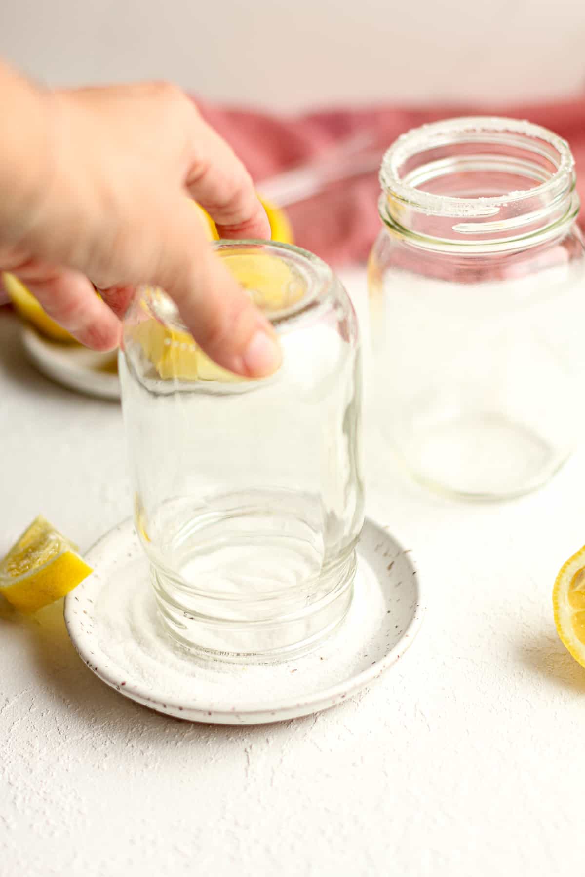 A hand pressing a glass jar in a plate of sugar.