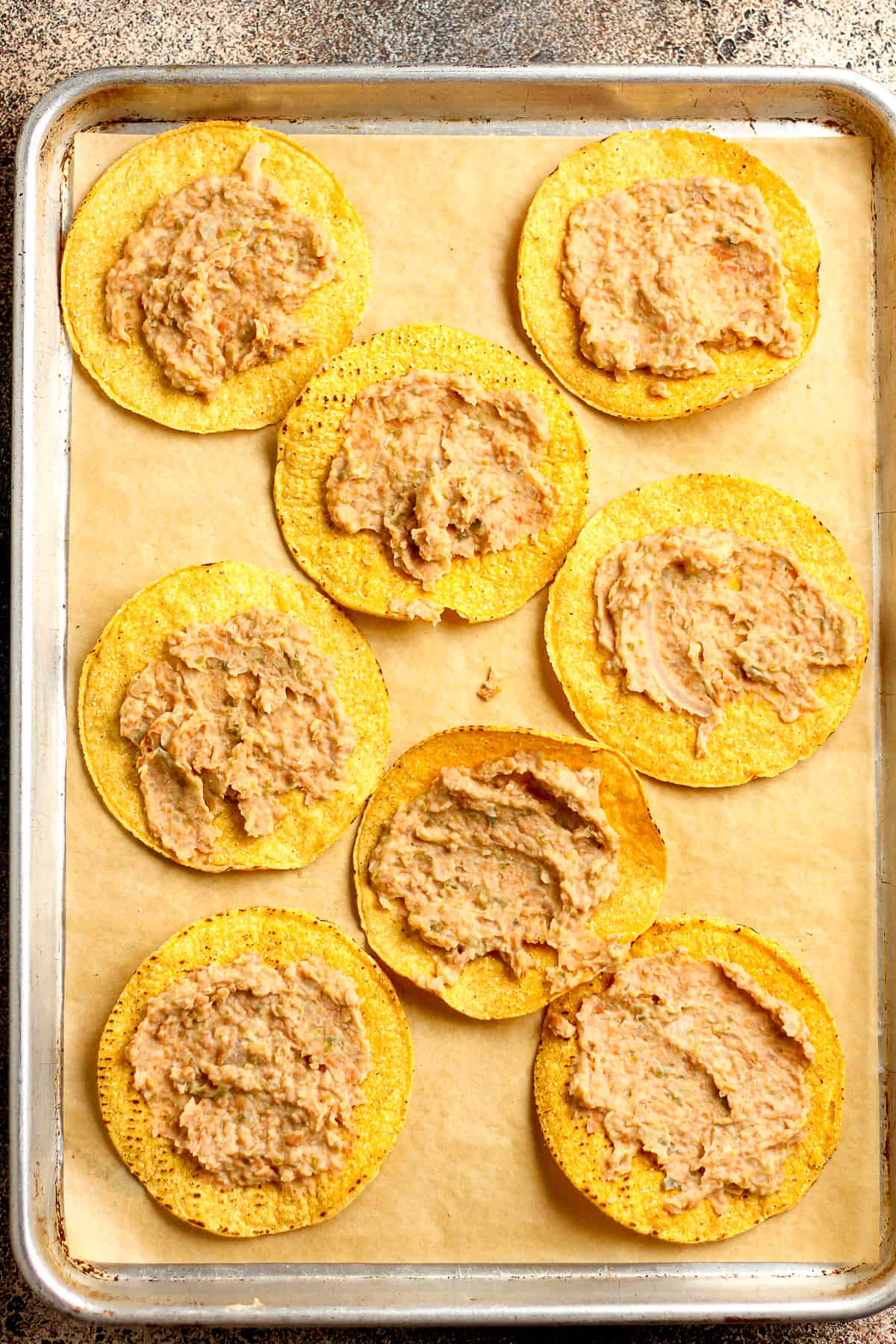 A pan of the tostadas with refried beans on top.