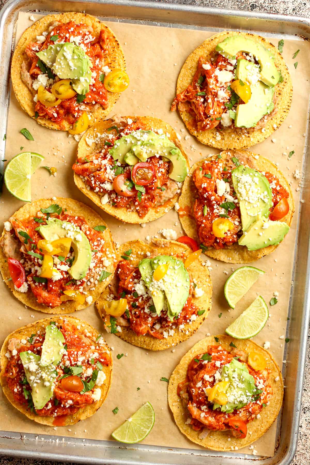 Overhead view of a large sheet pan of just made Tinga tostadas, with cilantro and other toppings.