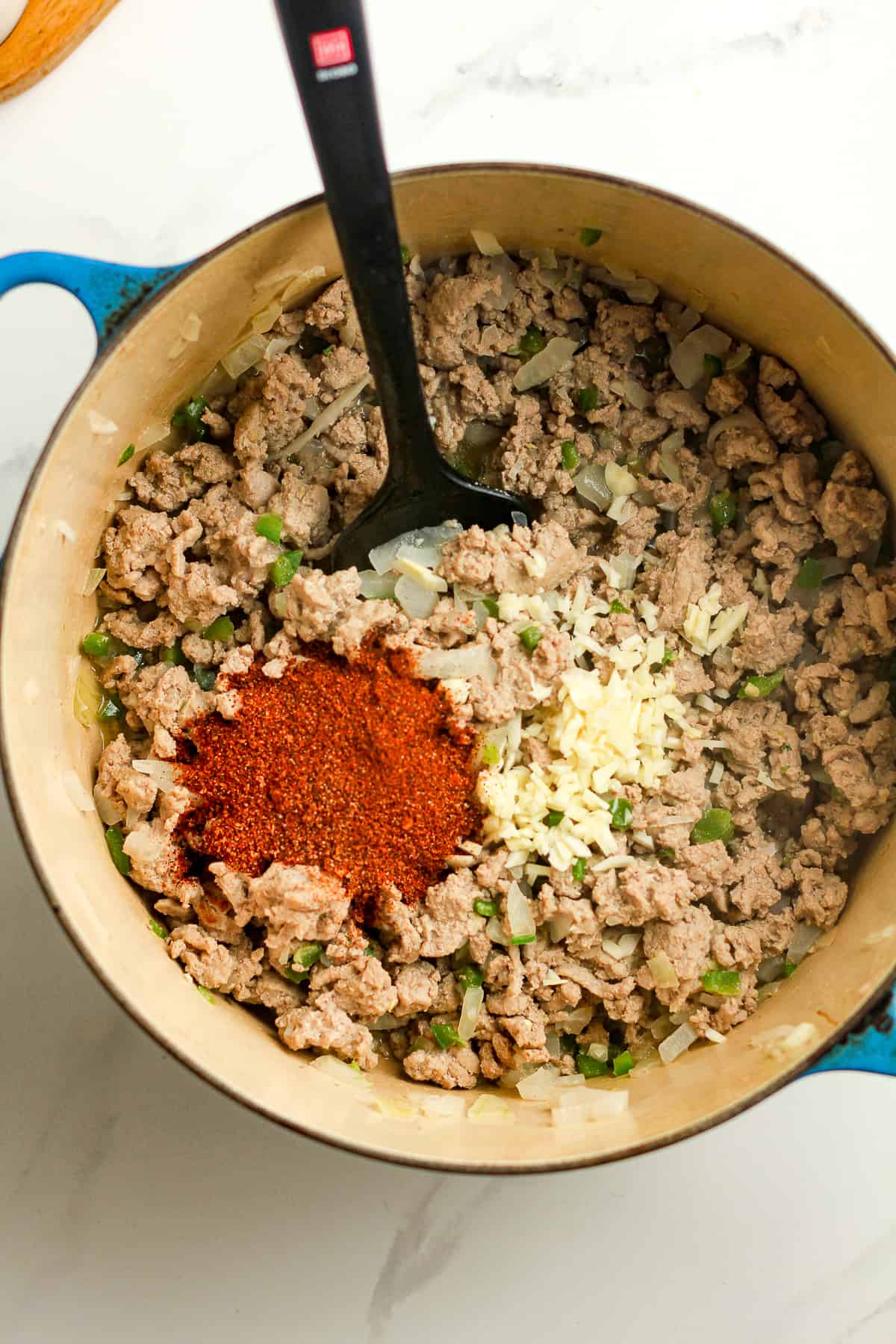 A pot of the ground turkey with the garlic and taco seasoning on top.