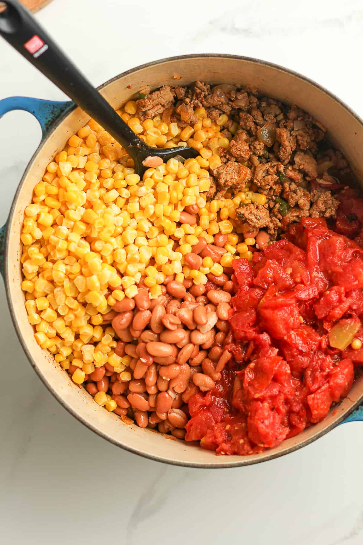 The soup pot with the corn, beans, and tomatoes on top.