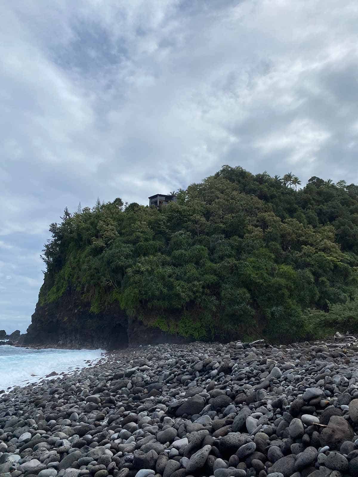 View from the beach of a cliff with the airbnb on top.