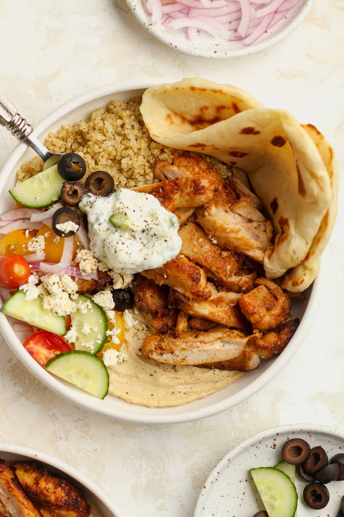 A bowl of chicken hummus bowls with quinoa and naan.