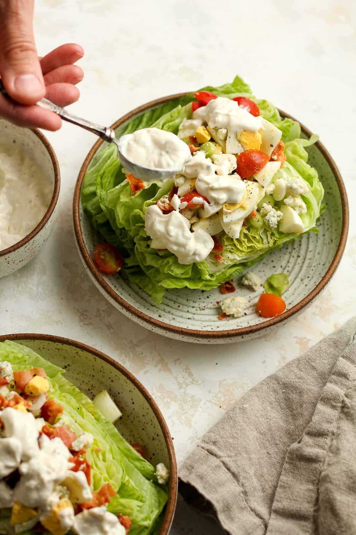 A spoon of blue cheese dressing being added to wedge salad.