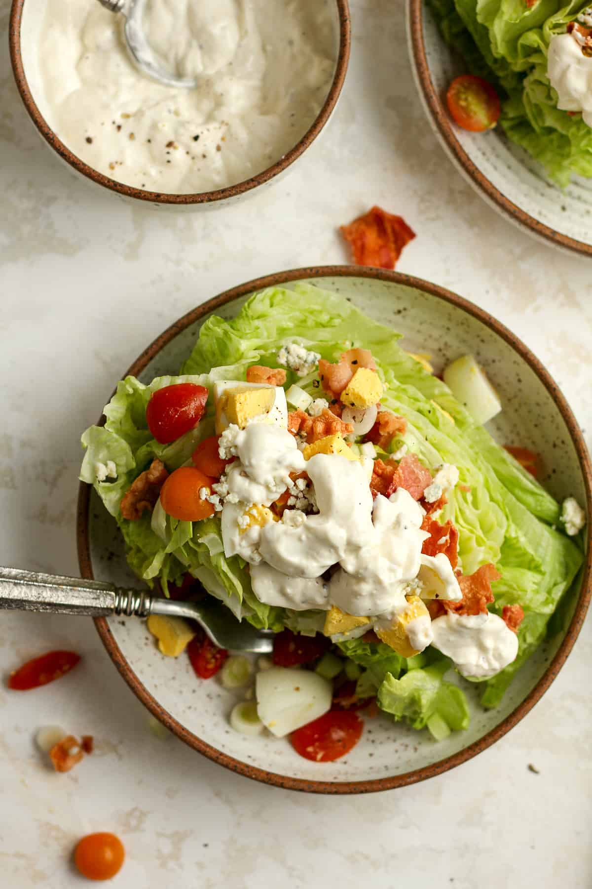 A wedge salad with toppings and blue cheese dressing.