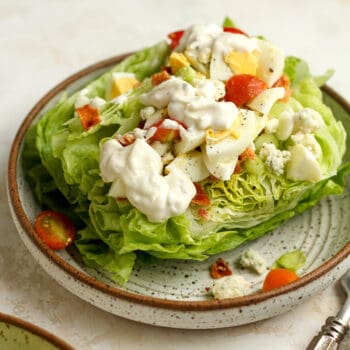 Side view of a bowl of wedge salad with blue cheese dressing and toppings.