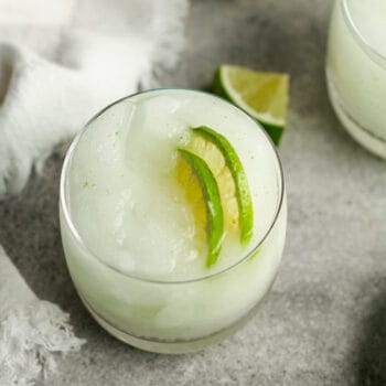 Closeup on a frozen gin and tonic with lime slices.