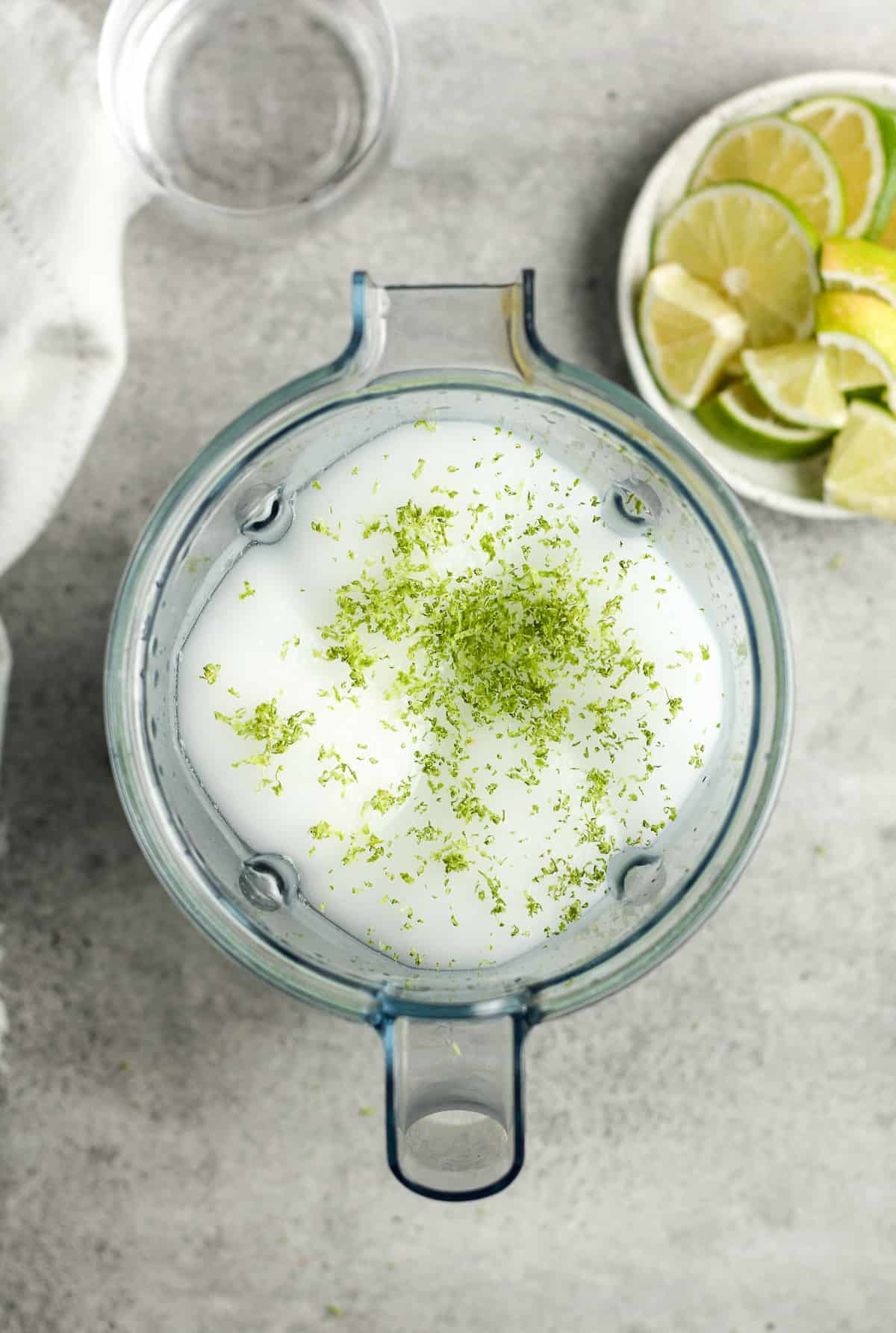 A blender with the blended gin and tonics with the lime zest on top.