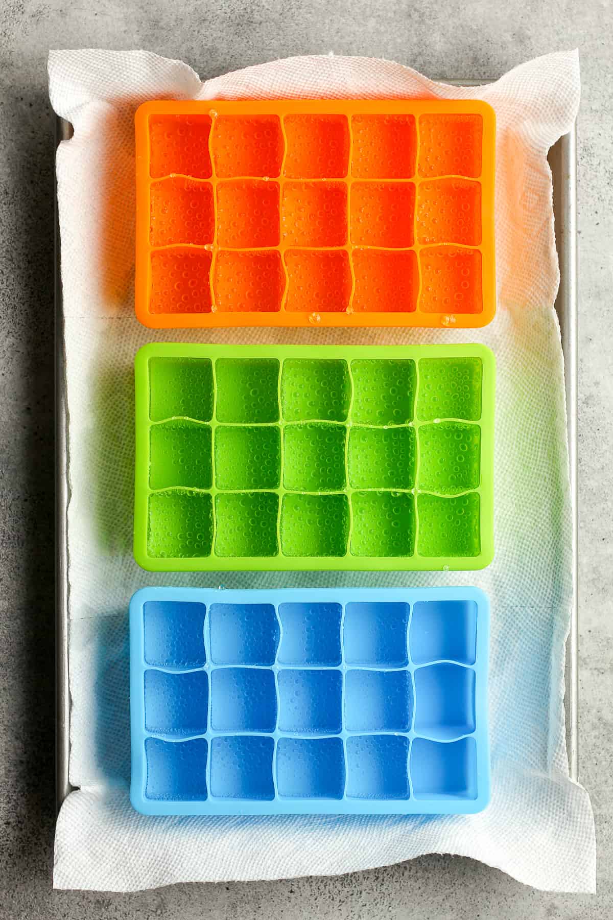 A pan of three ice cube trays filled with tonic water.