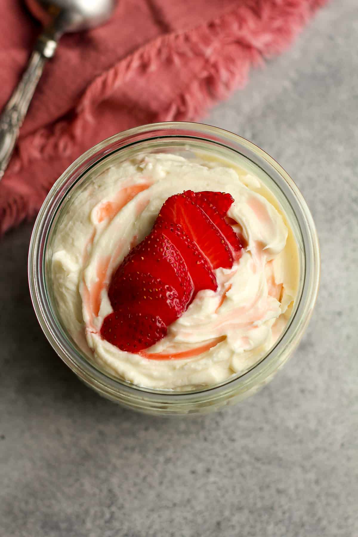 Overhead shot of a jar of fruit dip with sliced strawberries on top.