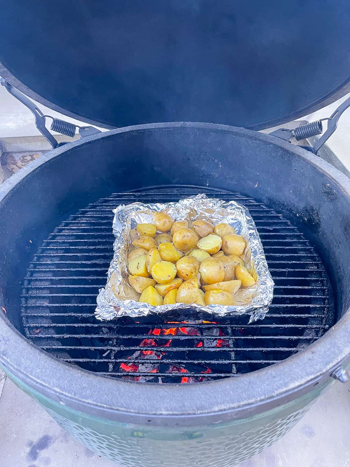 The Big Green Egg with tin full of potatoes.
