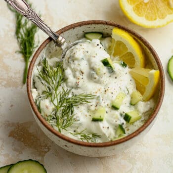 A spoonful in a bowl of healthy tzatziki sauce with fresh dill.
