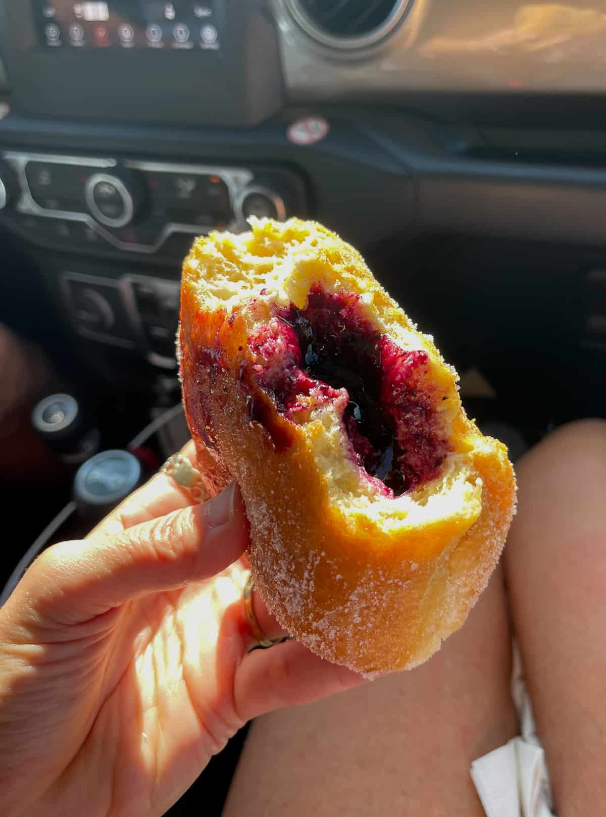Me holding a berry malasada in the car.