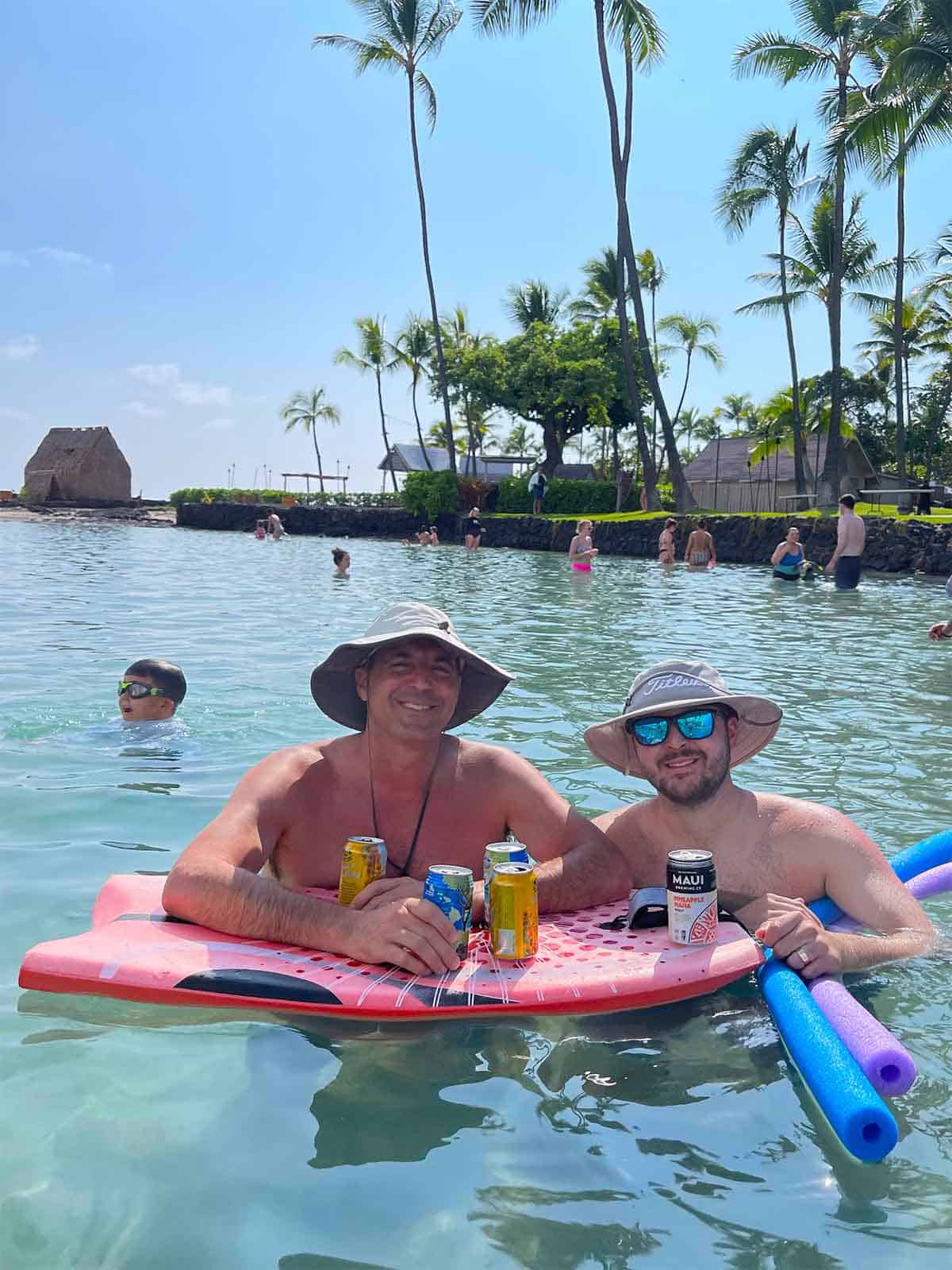 Mike and Josh with beers in the ocean.