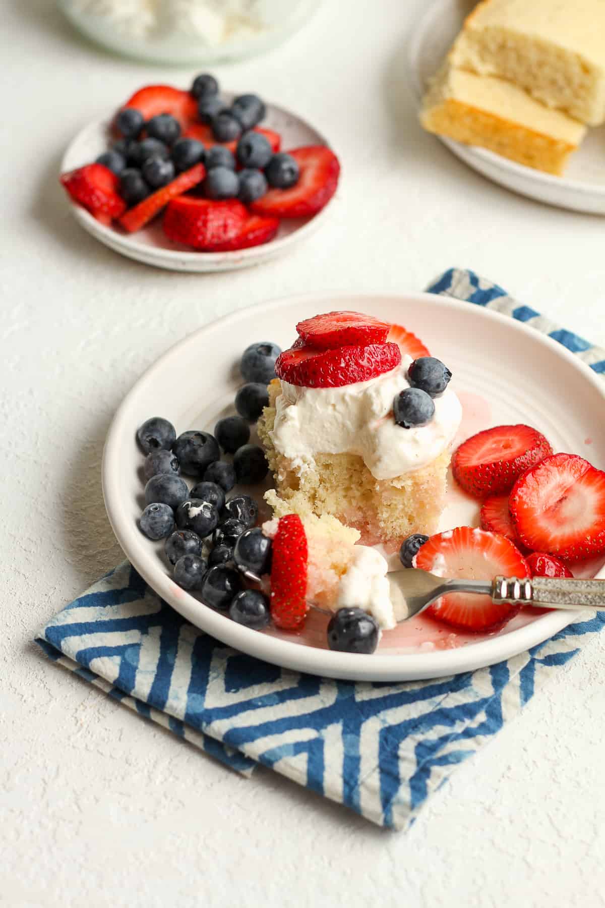 Side view of a plate of strawberry shortcake with blueberries.