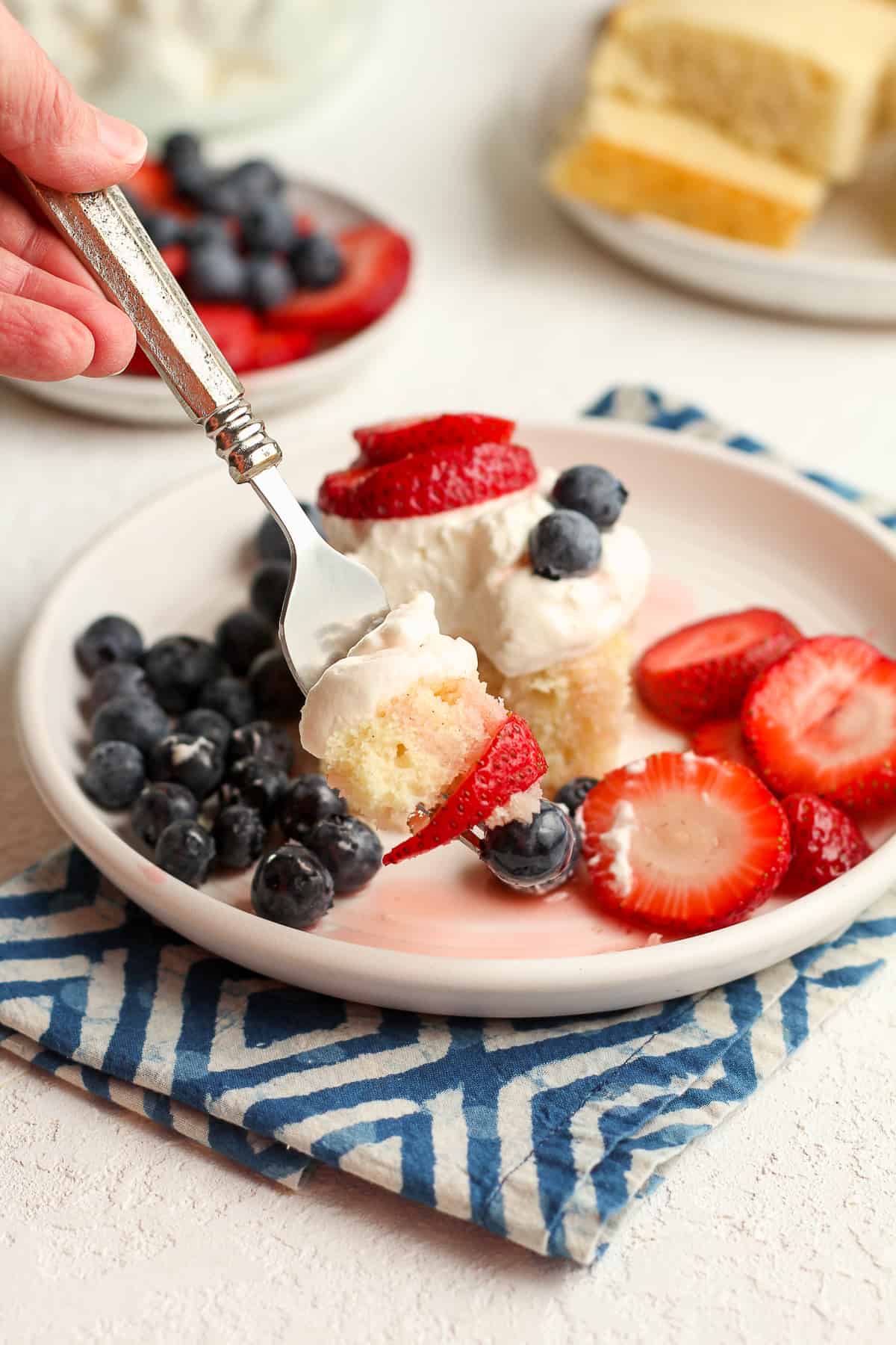 A forkful of moist strawberry shortcake on a white plate.