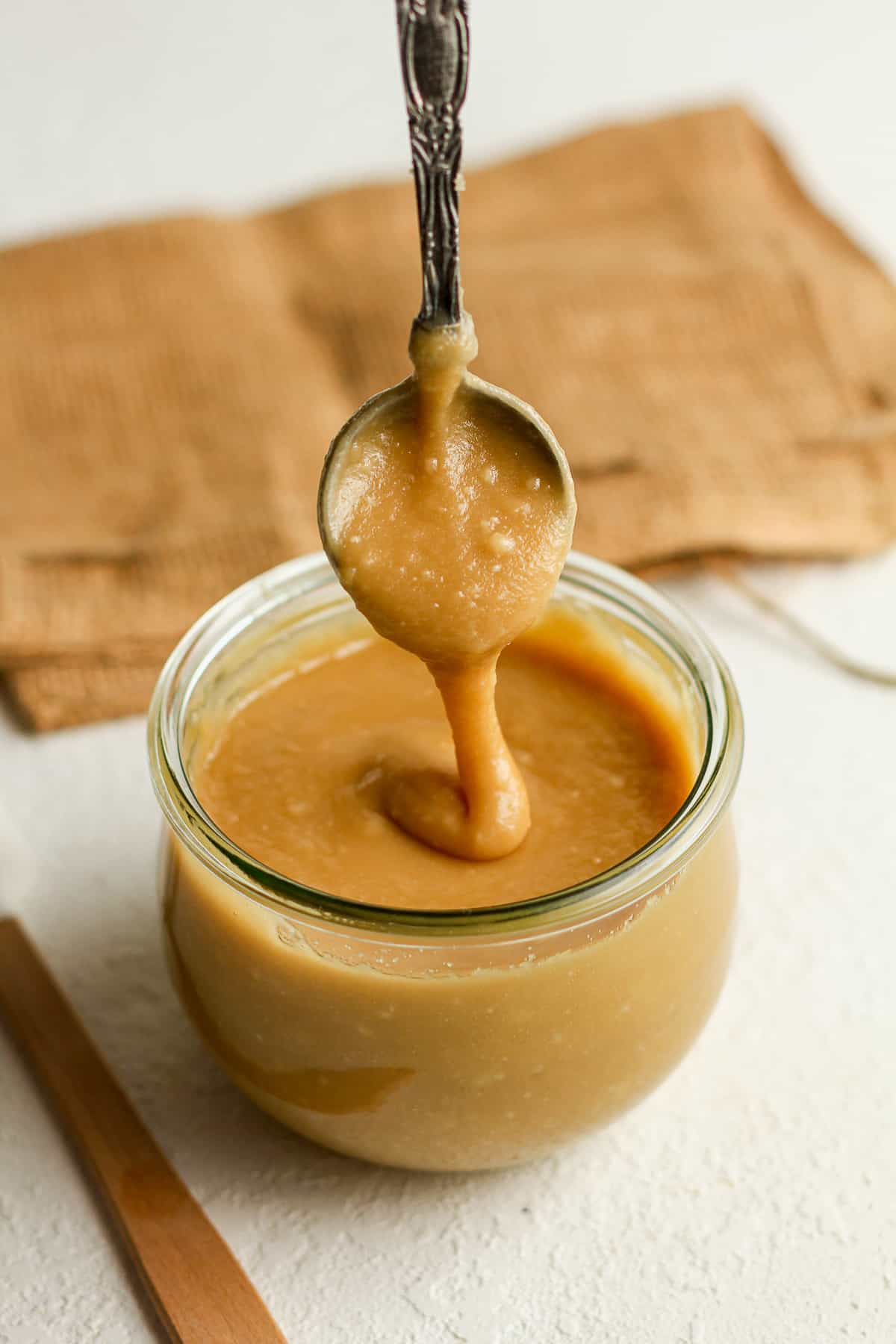 The caramel frosting drizzling off a spoon into a jar.