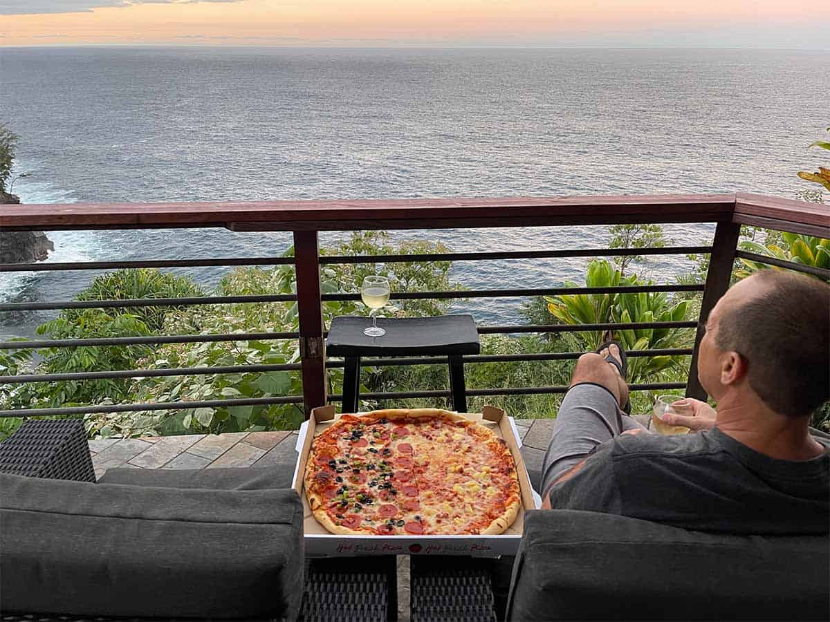 A view of the ocean with a pizza and wine.