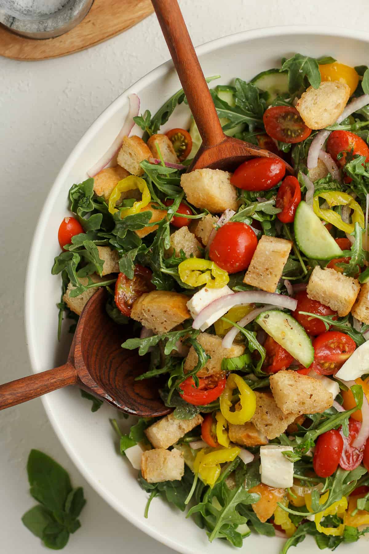 Closeup on a bowl of panzanella salad with wooden spoons.