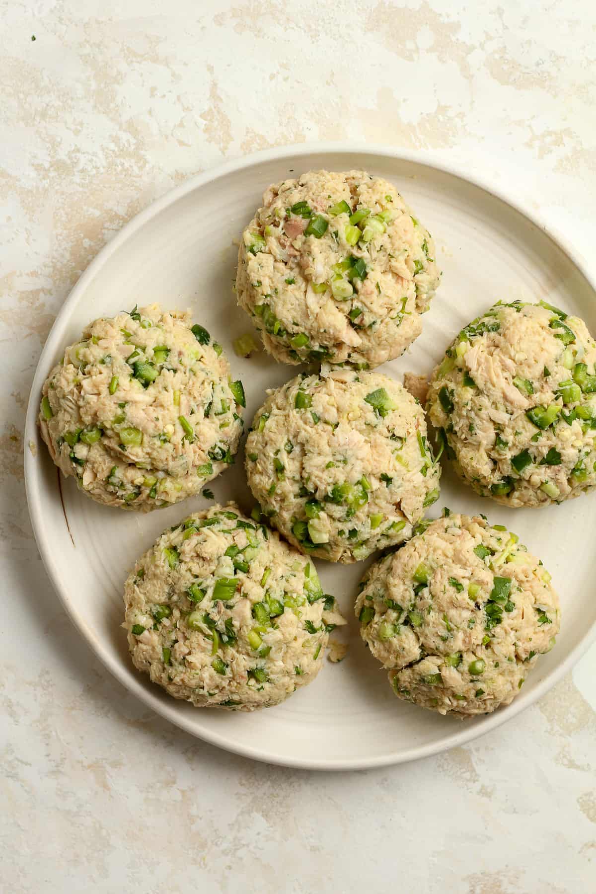A plate of six tuna patties before cooking.