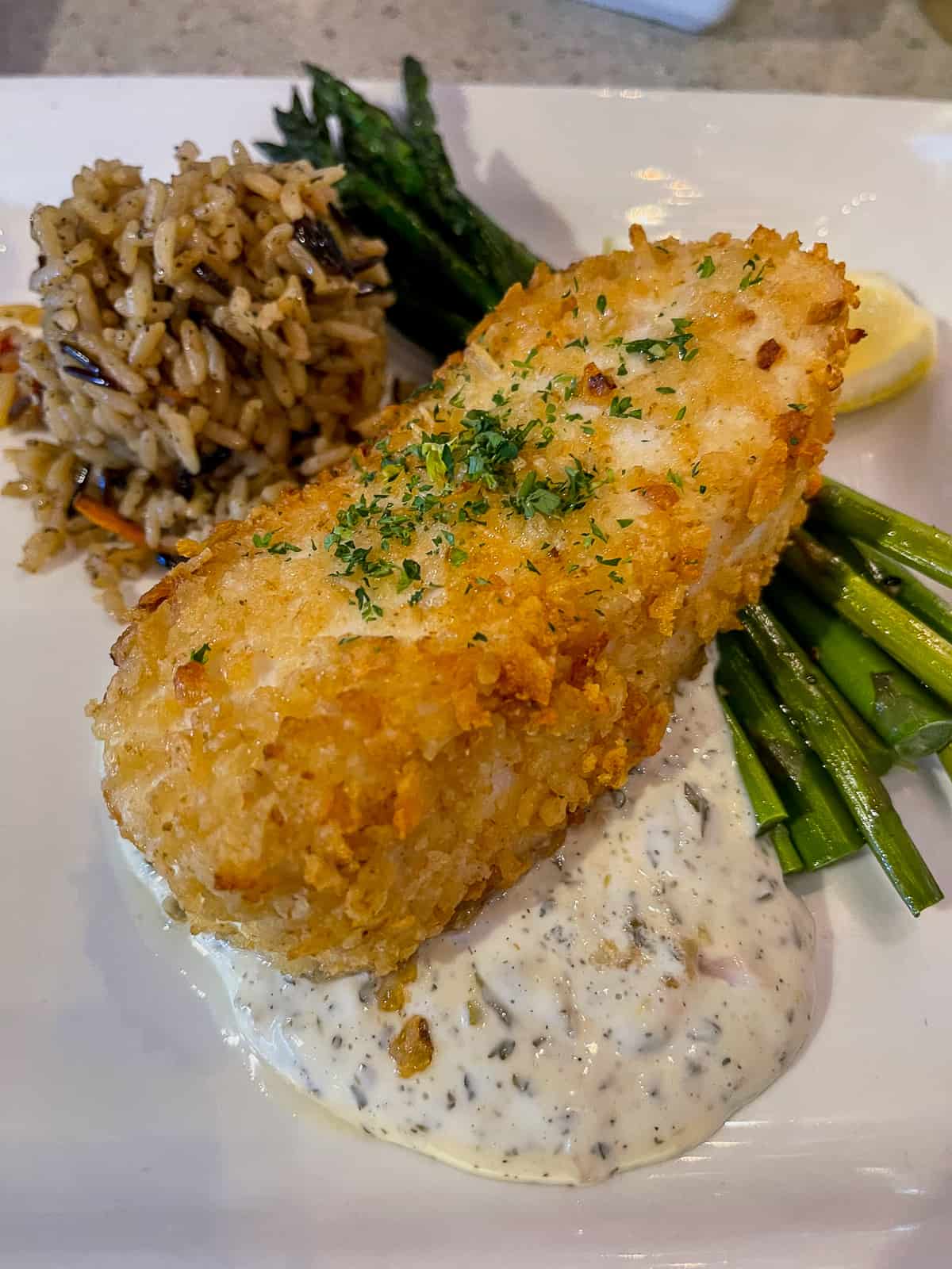 A plate of halibut on tarter sauce with asparagus.