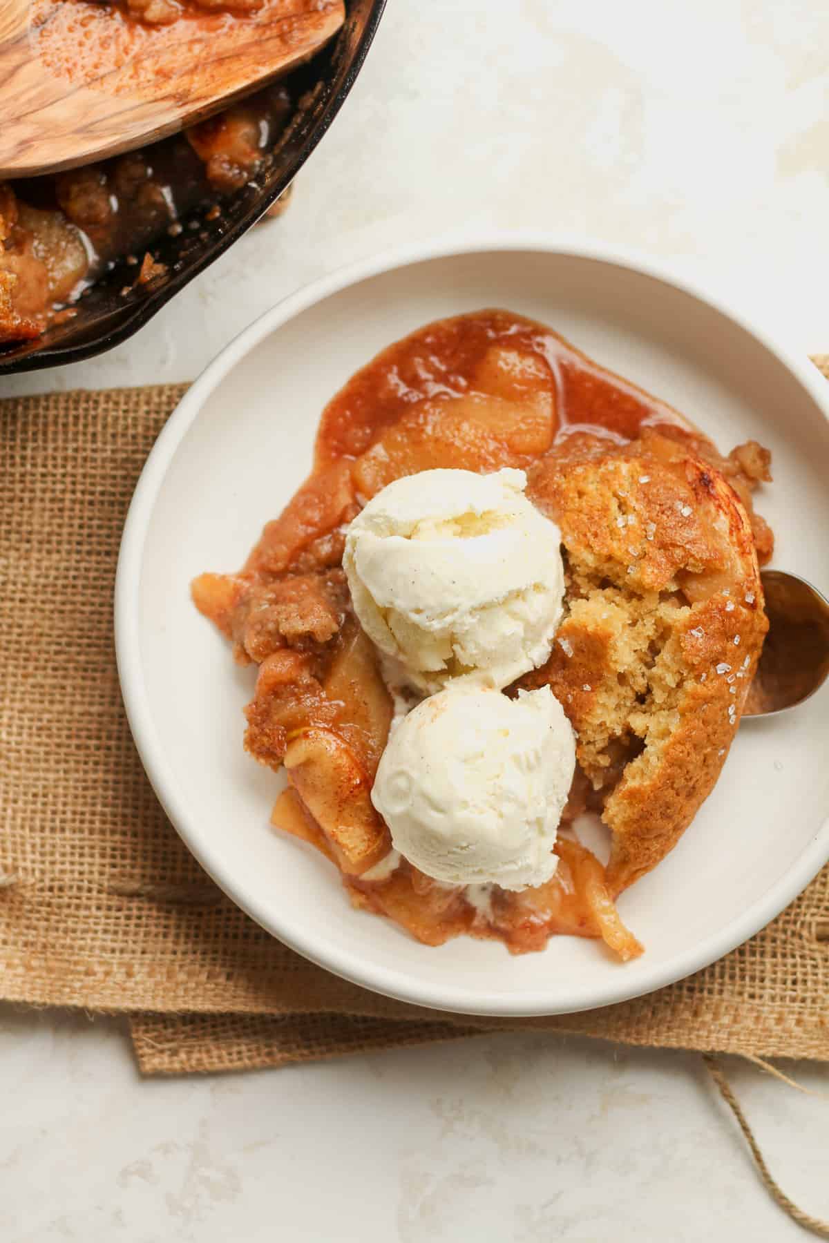A bowl of apple cobbler with two scoops of ice cream.