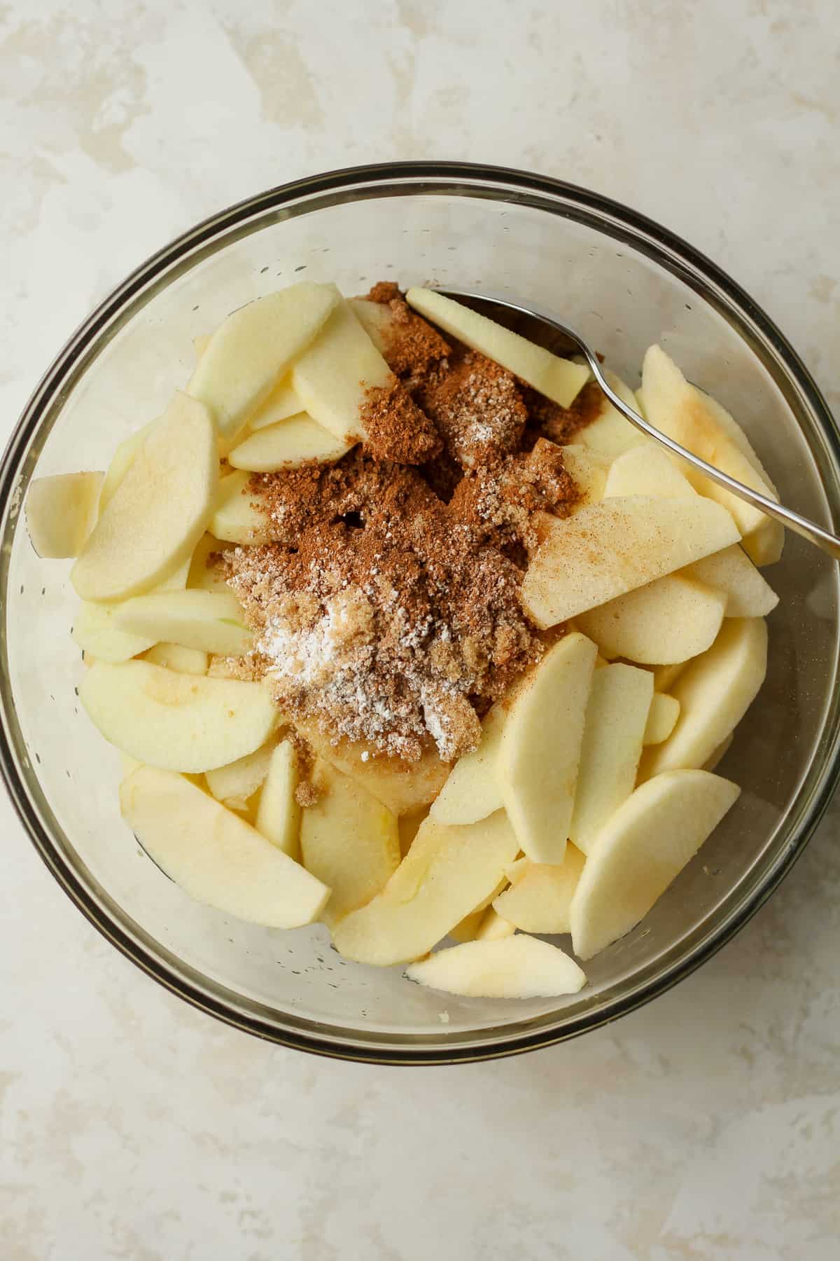 A bowl of the peeled and sliced apples with the cinnamon sugar mixture.
