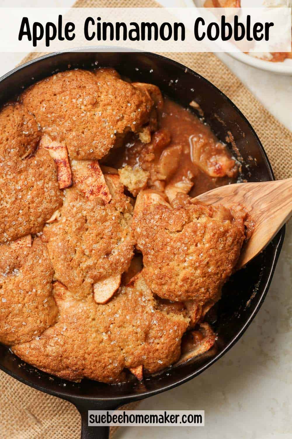 A skillet of apple cobbler with a spoon lifting some out.