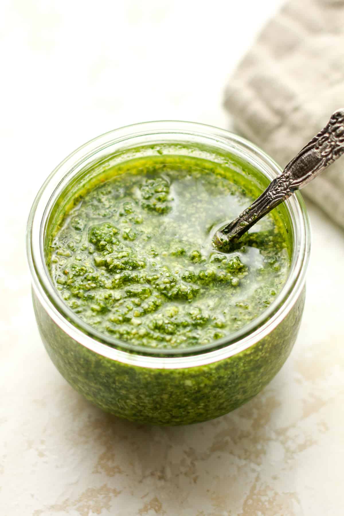 A jar of the homemade pesto sauce with a tablespoon.